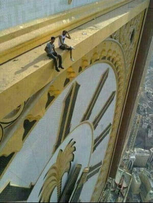 Два человека сидят на Королевской башне Makkah Clock в Мекке, самой высокой часовой башне на Земле