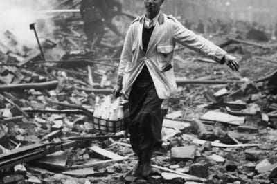 Молочник розвозить молоко на лондонській вулиці, розбомбленій Німеччиною, а пожежники гасять руїни, 1940 рік.