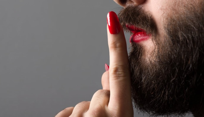 Бородатий чоловік з червоною помадою на губах і лаком на нігтях