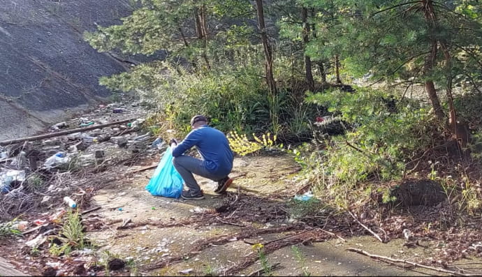Олександр з Білорусі прибирає у польському лісі