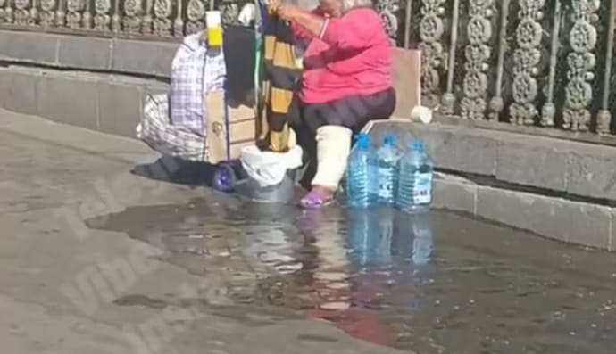 Женщина стирает одежду возле железнодорожного вокзала в Киеве