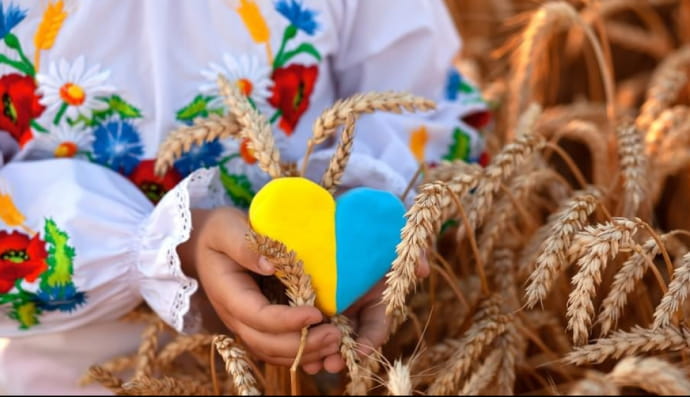 Дитина у вишиванці тримає сердечко, розмальоване у жовто-сині кольори