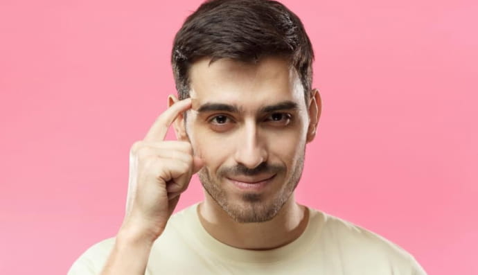 Чоловік, який вказує пальцем на скроню