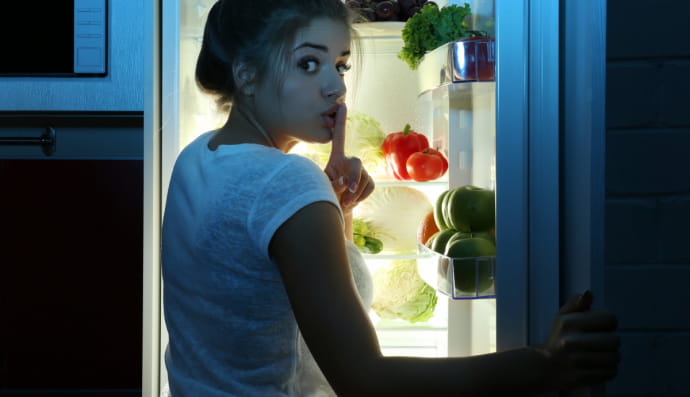 Жінка вночі поблизу холодильника