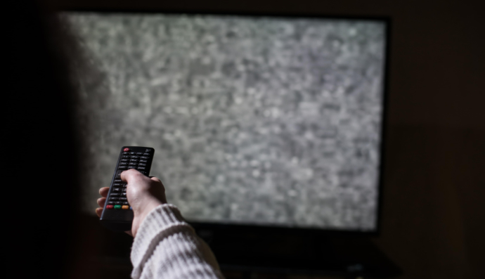 Женщина сидит перед сломанным телевизором