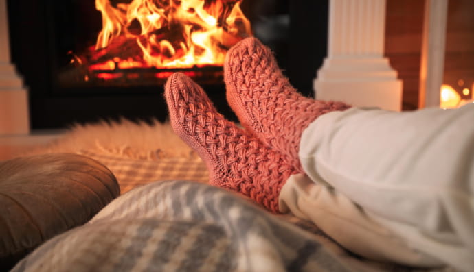 Жінка у теплих шкарпетках відпочиває біля каміна