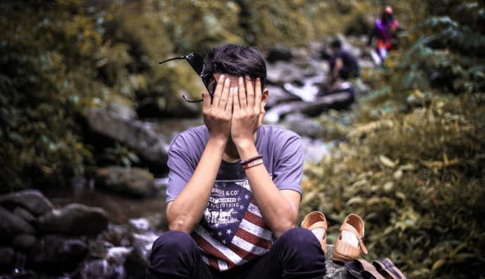 Человек прикрывает лицо руками